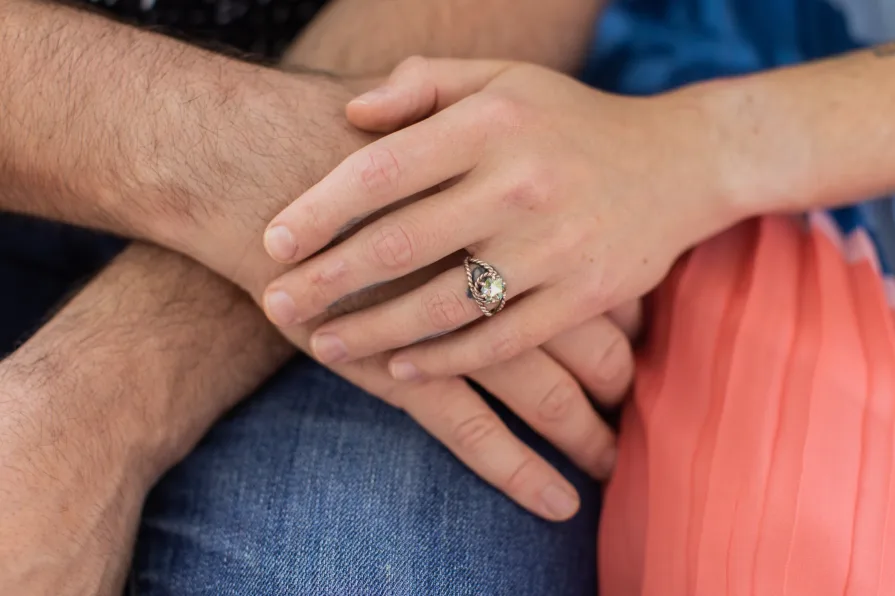 Overlapping hands, with one of them having an engagement ring.