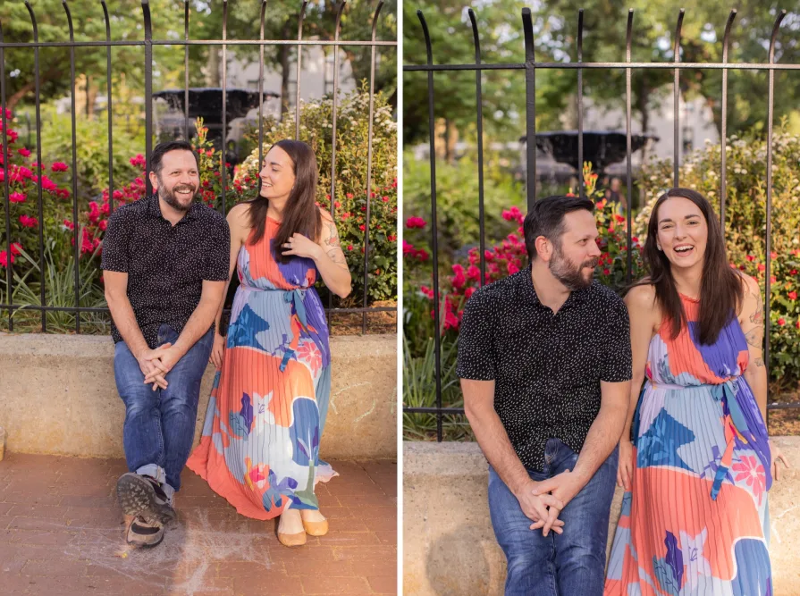 A couple laughing and sitting alongside a fenced area.