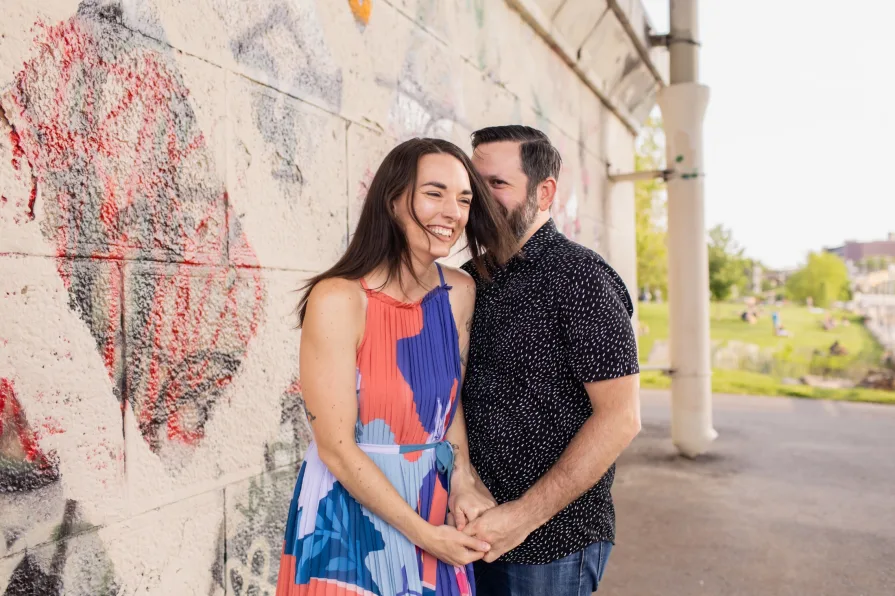 Two engaged folks smiling in Schuylkill River Park.