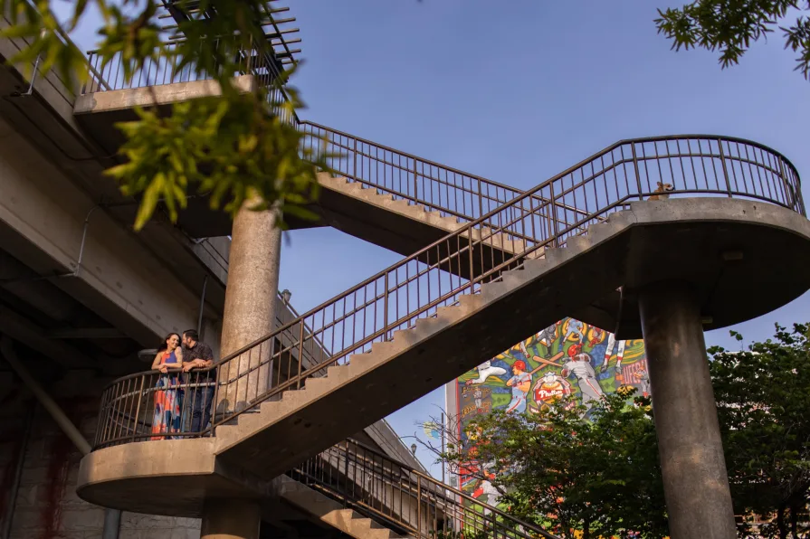 An engaged couple kissing while sitting on the grass in Schuylkill River Park.