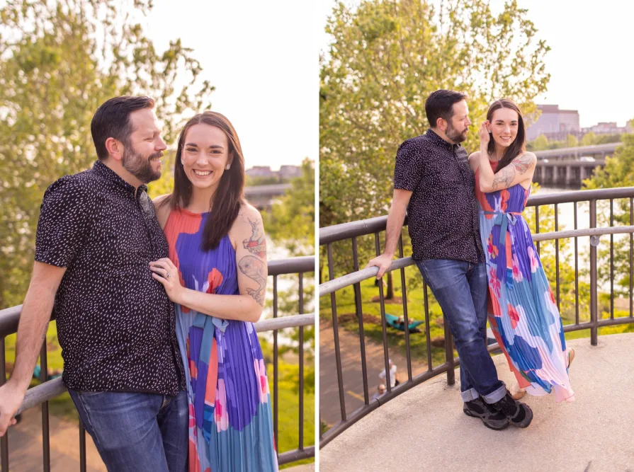An engaged couple kissing while sitting on the grass in Schuylkill River Park.