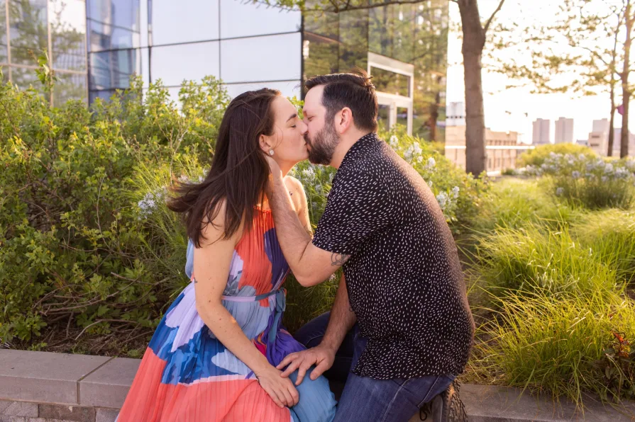 An engaged couple smiling and dancing in front of the Philadelphia skyline at Cira Green's rooftop .