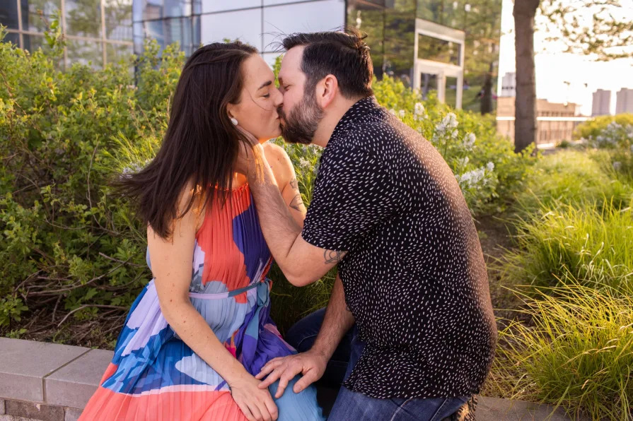 An engaged couple smiling and dancing in front of the Philadelphia skyline at Cira Green's rooftop .