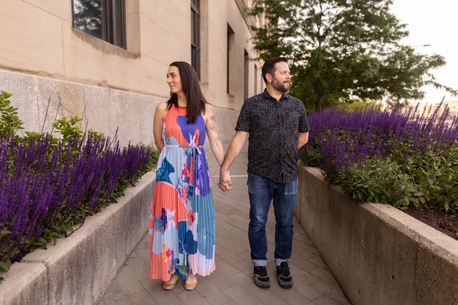 A couple standing in a floral-lined path near 30th Street Station.
