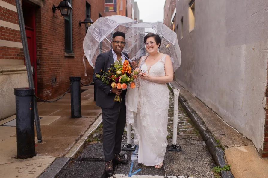A queer, biracial couple in the rain on their wedding day in a Philadelphia alleyway.
