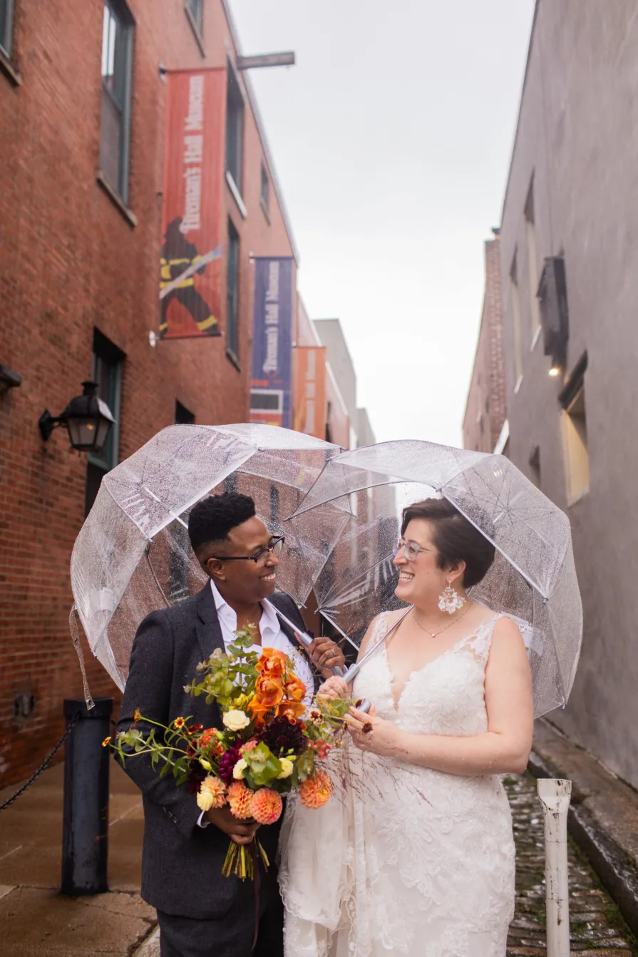 A queer, biracial couple in the rain on their wedding day in a Philadelphia alleyway.