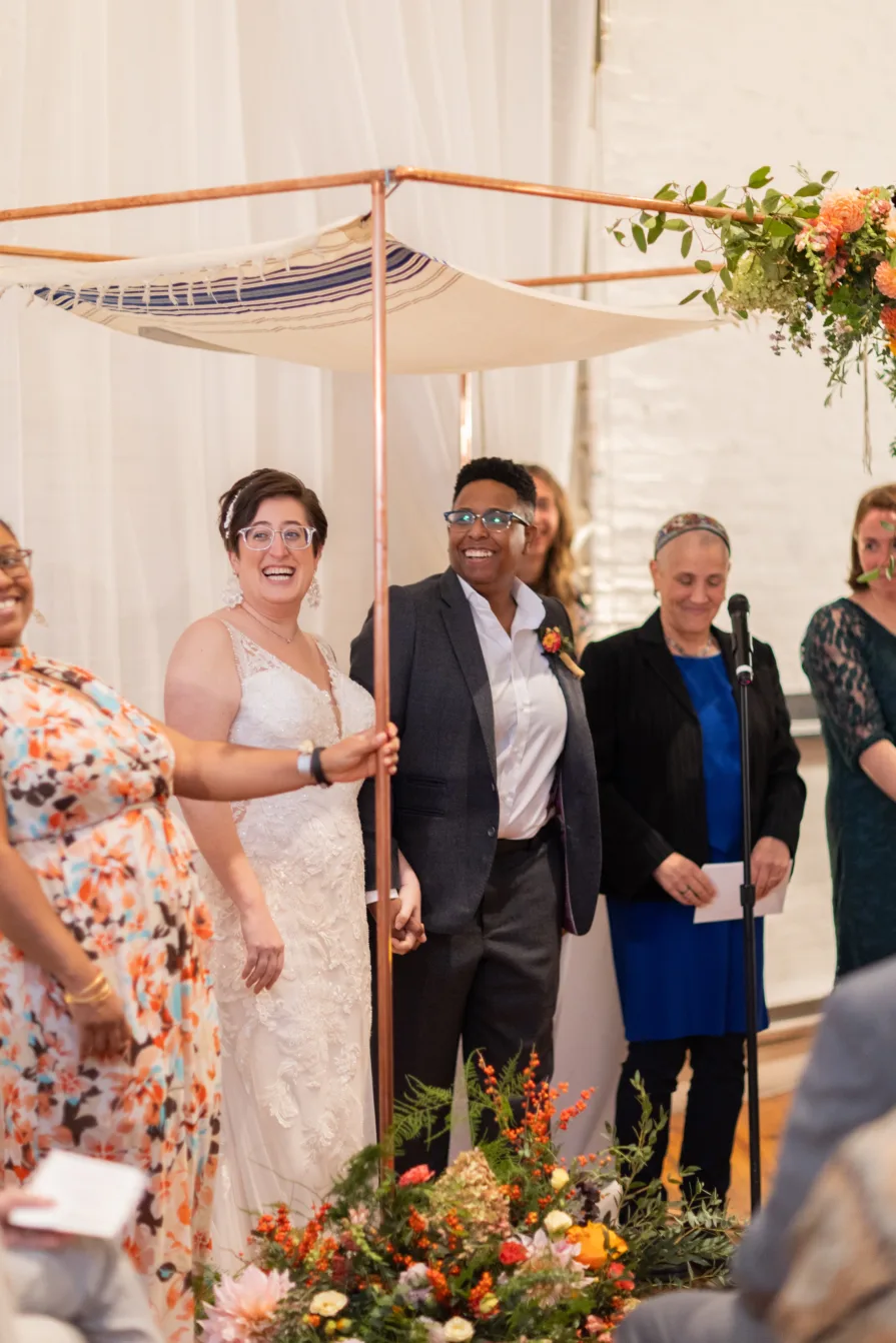 Marriers under a chuppah smile during their ceremony.