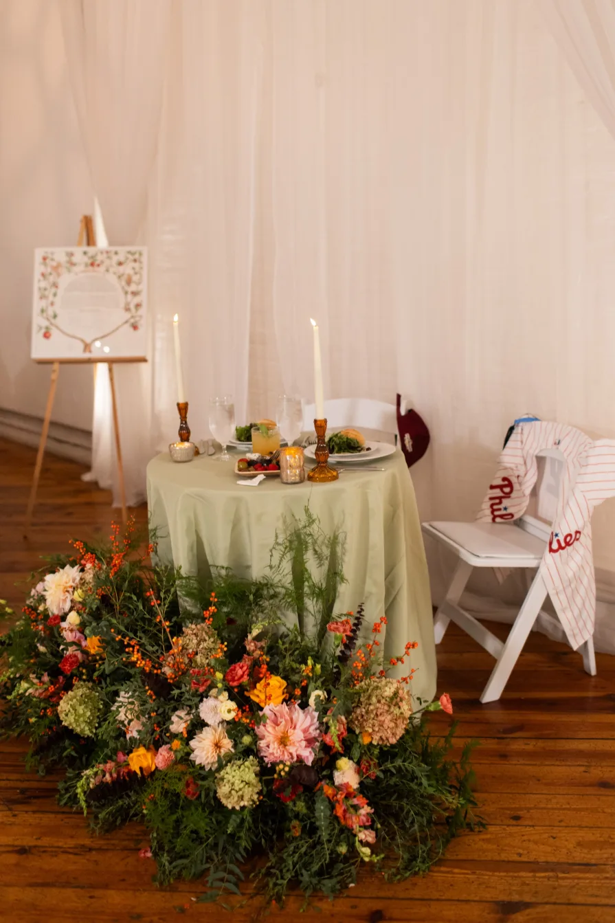 A sweetheart table with flowers and Phillies gear.