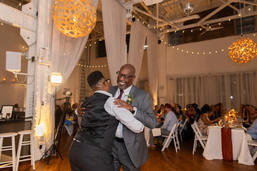 A queer, biracial couple during their parent dances at an Old City wedding at Power Plant.