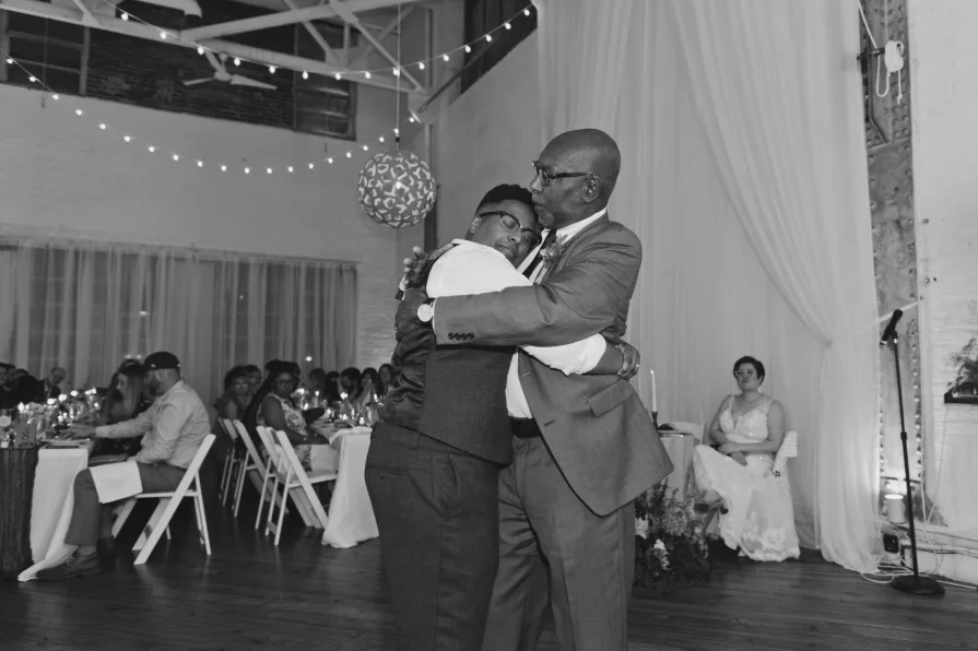 A queer, biracial couple during their parent dances at an Old City wedding at Power Plant.