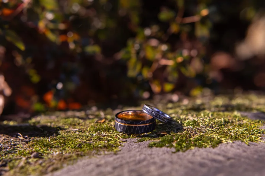 Marrier's wedding bands on a mossy path stone wall.