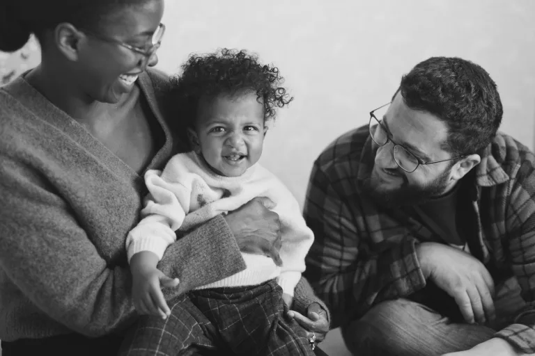 A black and white of an interracial couple with their one-year-old during a family photo session.