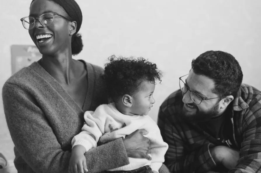 A black and white of an interracial couple with their one-year-old during a family photo session.