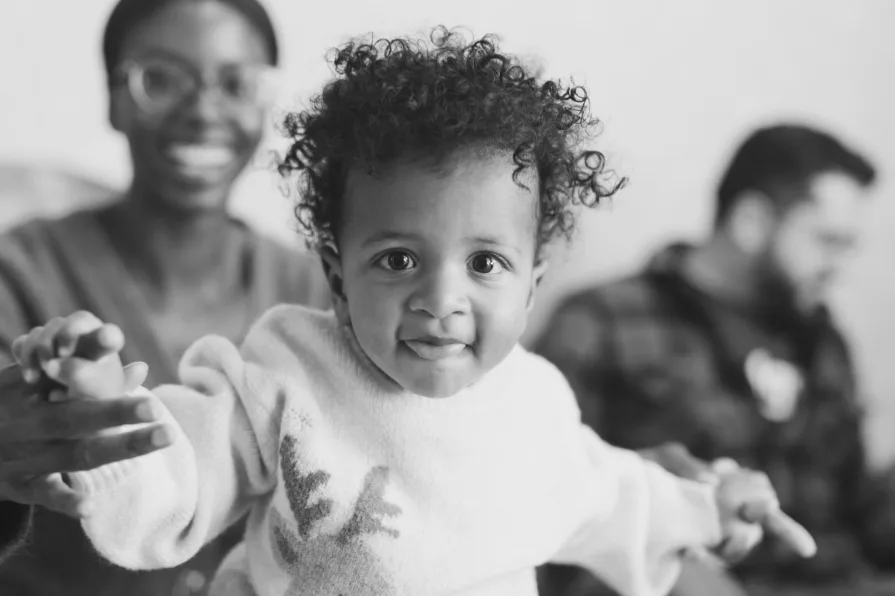 A black and white of an interracial couple with their one-year-old during a family photo session.