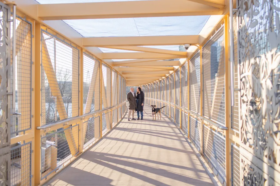 A couple smiling on a bridge after getting engaged.