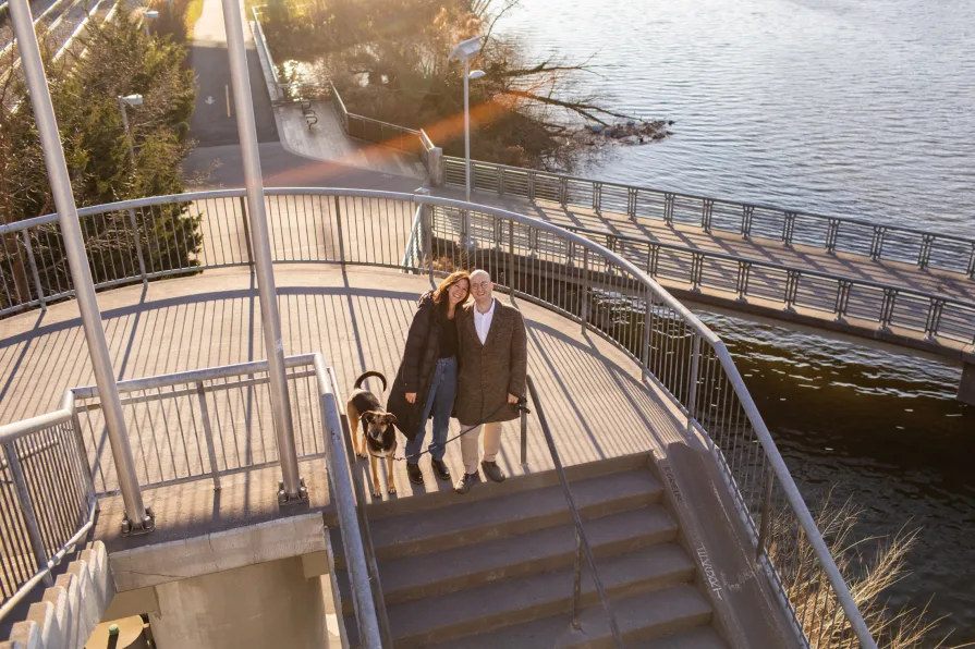 A couple walking with their dog near Schuylkill River Trail after getting engaged in Philadelphia.