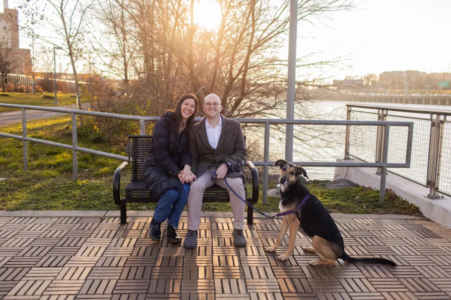 A couple walking with their dog near Schuylkill River Trail after getting engaged in Philadelphia.
