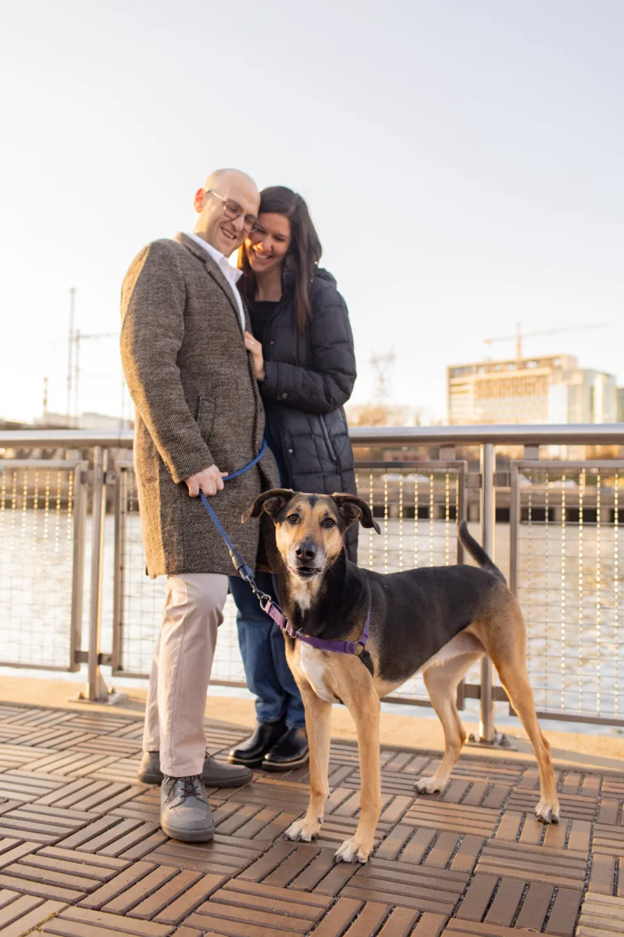 A couple walking with their dog near Schuylkill River Trail after getting engaged in Philadelphia.