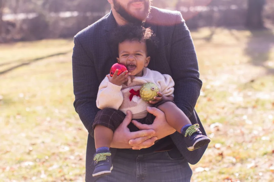 Forest's dad holds him while he plays with a Christmas ornament.