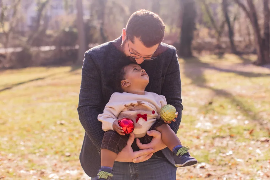 Forest's dad holds him while he plays with a Christmas ornament.