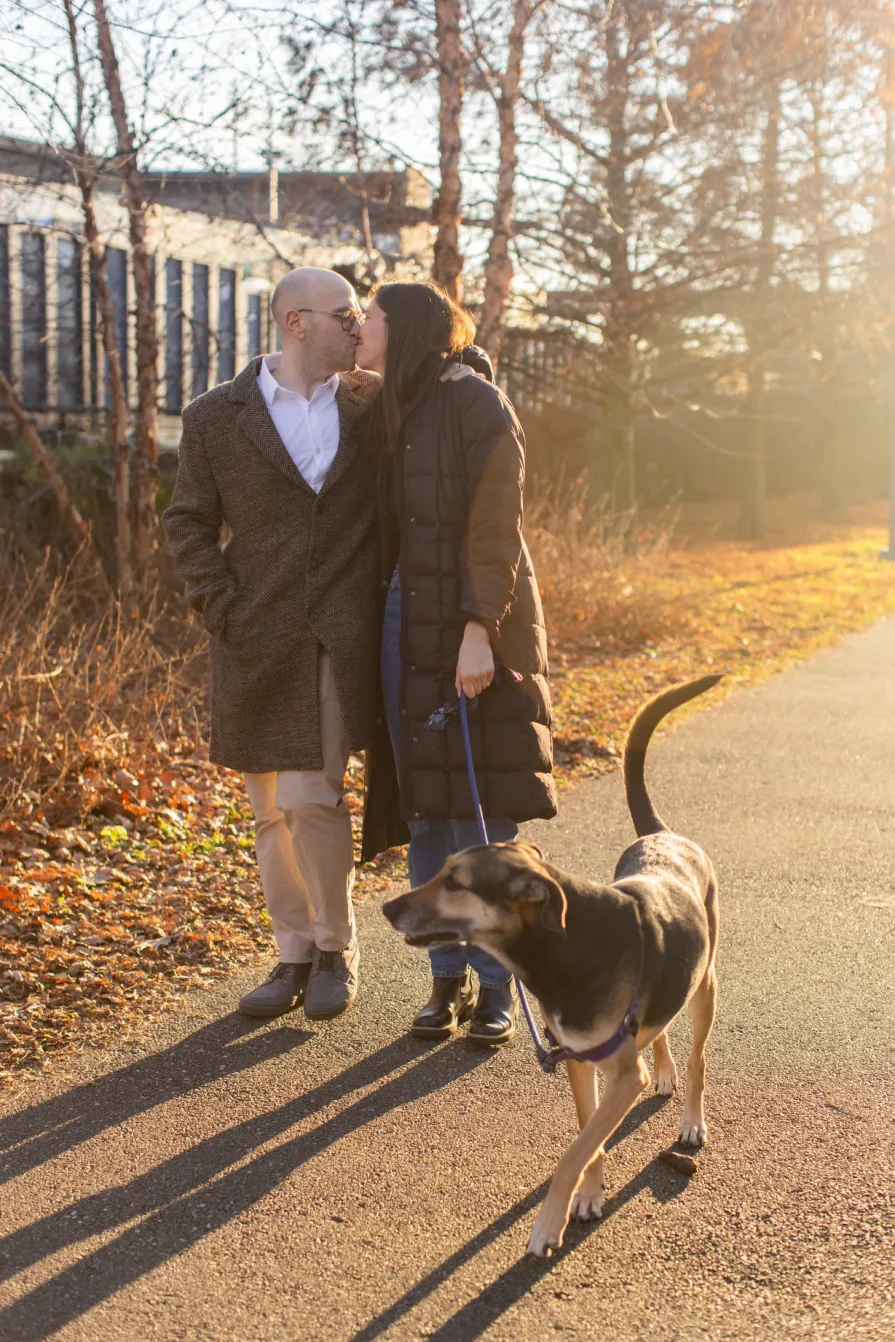 A couple walking with their dog near Schuylkill River Trail after getting engaged in Philadelphia.