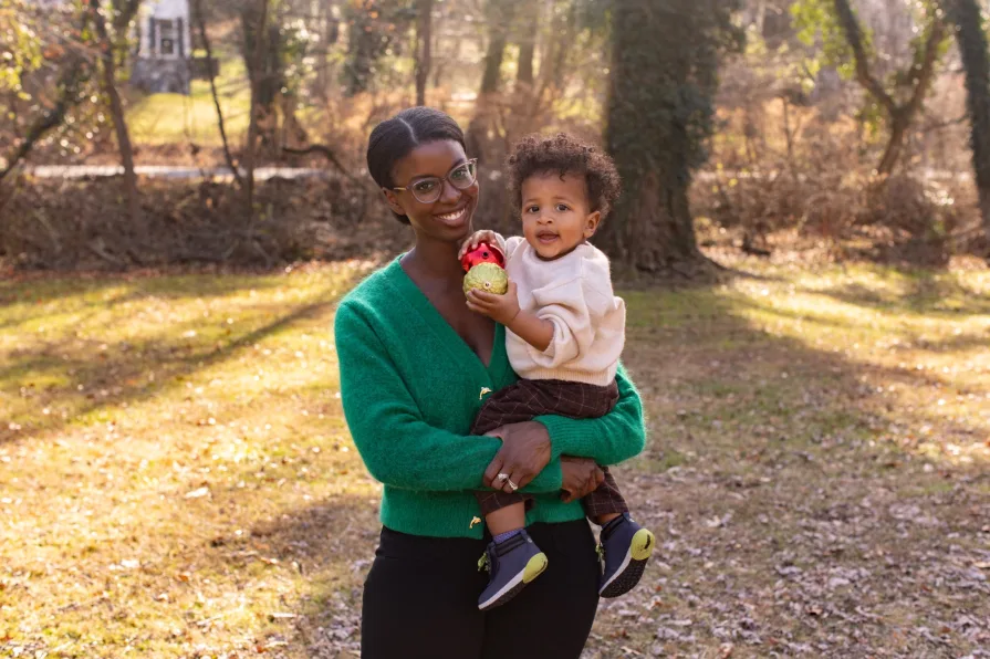 One-year-old Forest is held by his mom in their backyard during a family photo session.
