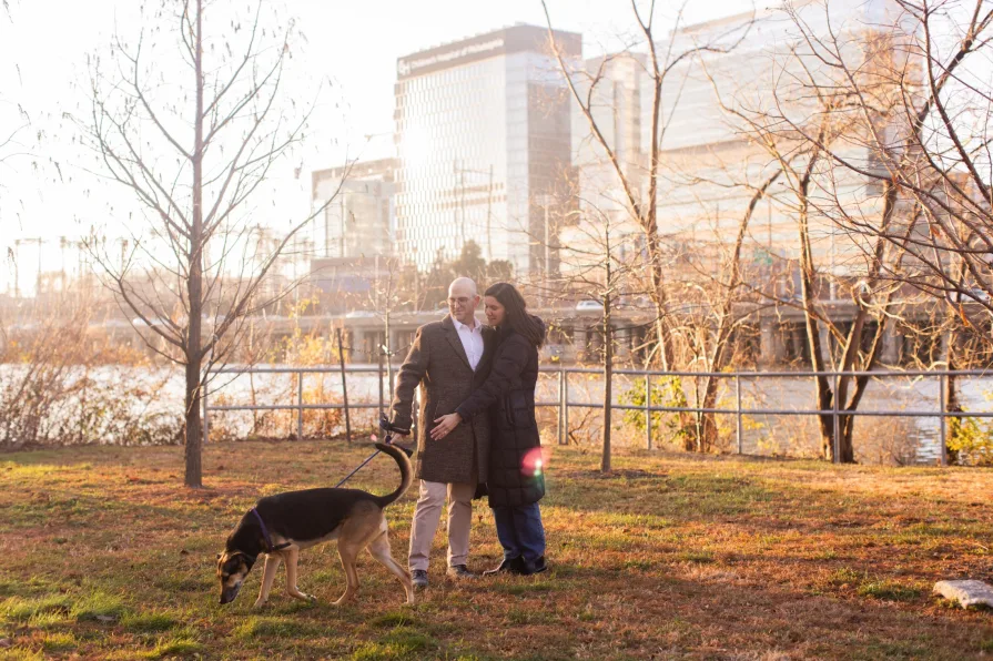 A couple walking with their dog near Schuylkill River Trail after getting engaged in Philadelphia.