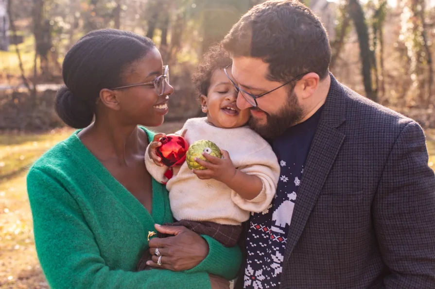 An interracial family of three in their backyard during a family photo session.