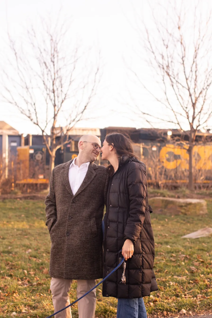 A couple walking with their dog near Schuylkill River Trail after getting engaged in Philadelphia.