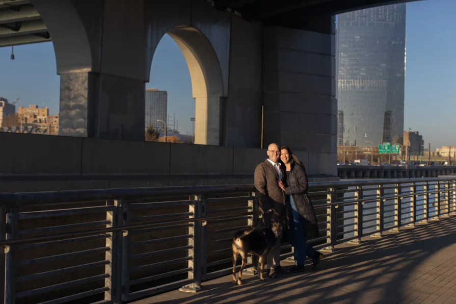A couple walking with their dog near Schuylkill River Trail after getting engaged in Philadelphia.