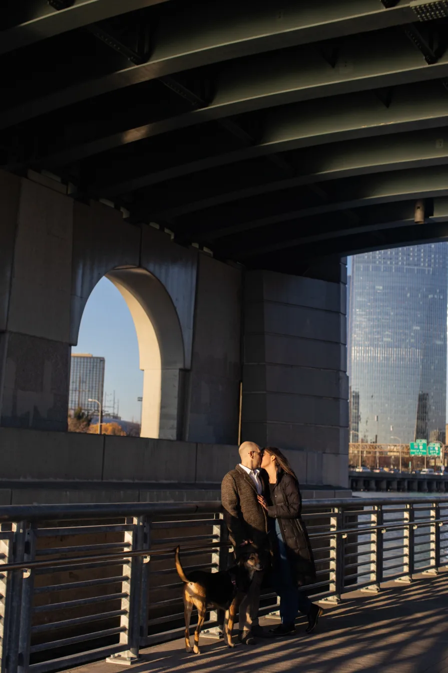 A couple walking with their dog near Schuylkill River Trail after getting engaged in Philadelphia.