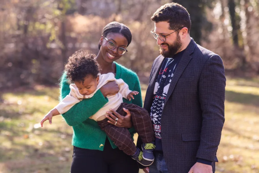 An interracial family of three in their backyard during a family photo session.