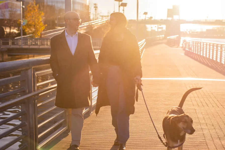 A couple walking with their dog near Schuylkill River Trail after getting engaged in Philadelphia.