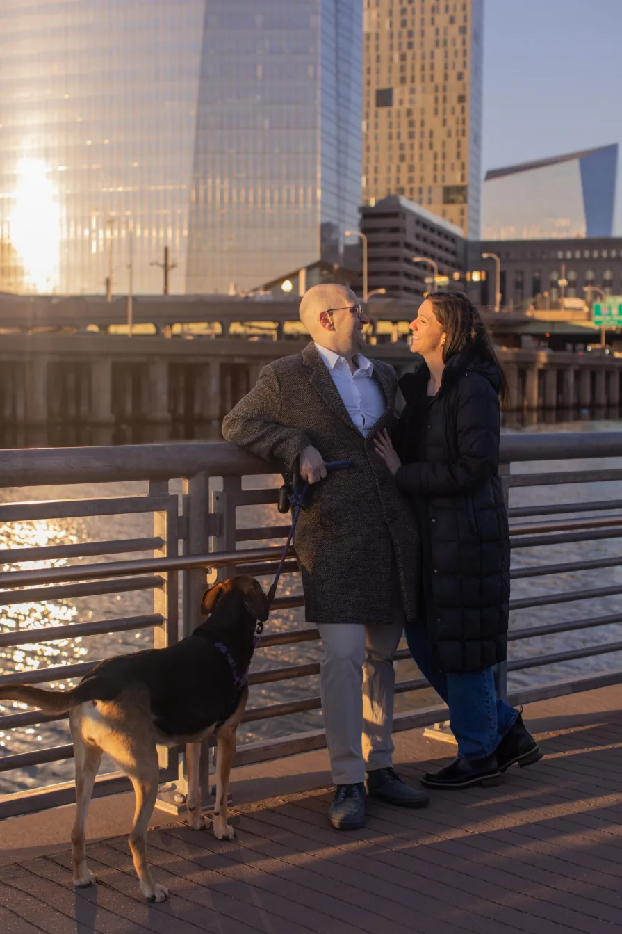 A couple walking with their dog near Schuylkill River Trail after getting engaged in Philadelphia.