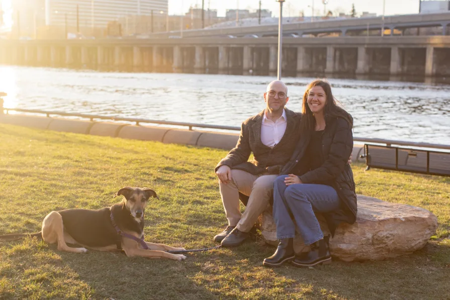 A couple walking with their dog near Schuylkill River Trail after getting engaged in Philadelphia.