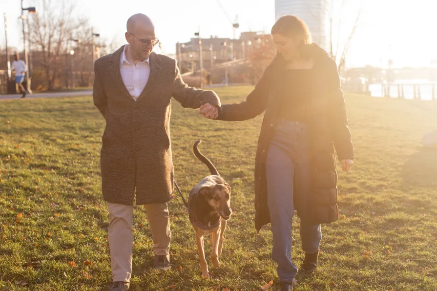 A couple walking with their dog near Schuylkill River Trail after getting engaged in Philadelphia.