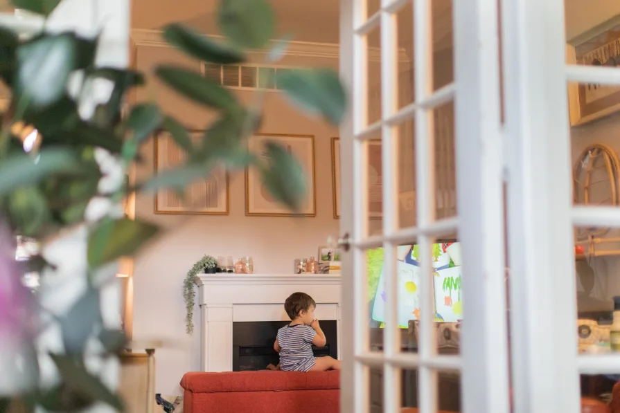 A toddler sits inside while watching a television show.