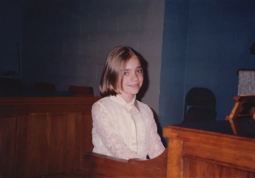 A photo of me in grade school making an uncomfortable smile during my piano recital.
