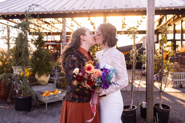 A queer couple has portraits taken at their Terrain Gardens Devon wedding in the fall.